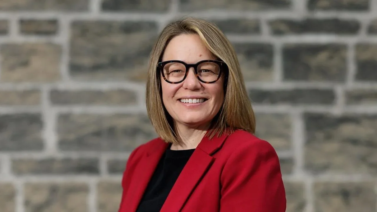 Hannah Buckley wearing a red blazer smiles and looks at the camera
