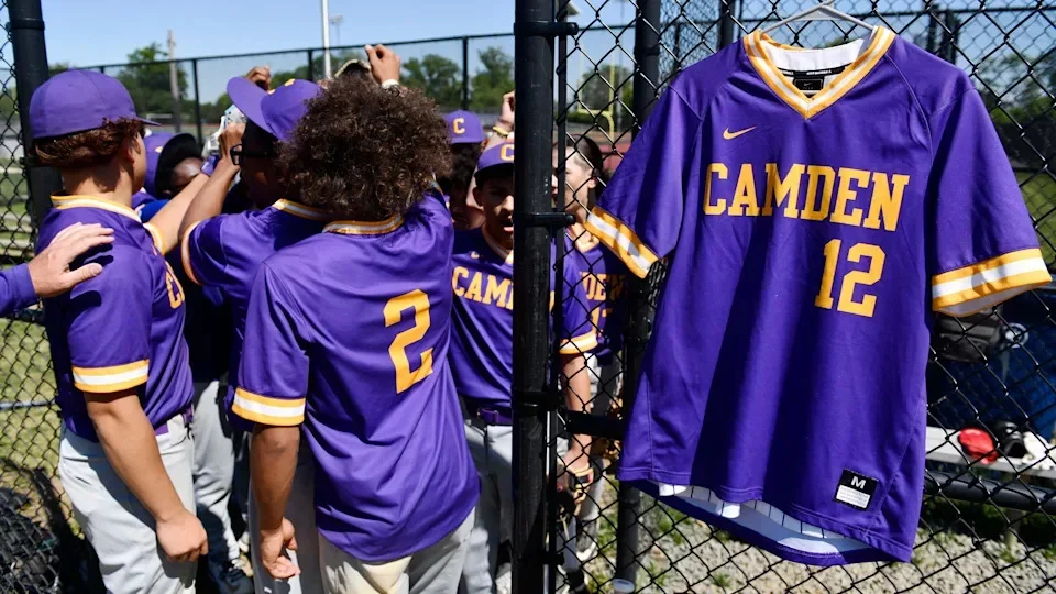 Members of the Camden High baseball team huddle together near the jersey of former Camden High School baseball player Joshwa Boston, who recently passed away, prior to the baseball game between Camden and Medford Tech at Farnham Park in Camden on Tuesday, May 12, 2026. The Camden baseball team has dedicated the season to Boston’s memory.”